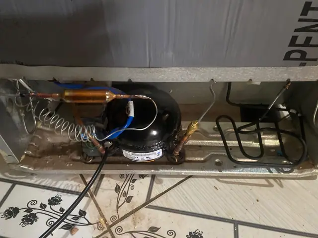 Compressor e serpentina na parte traseira de uma geladeira em manutenção